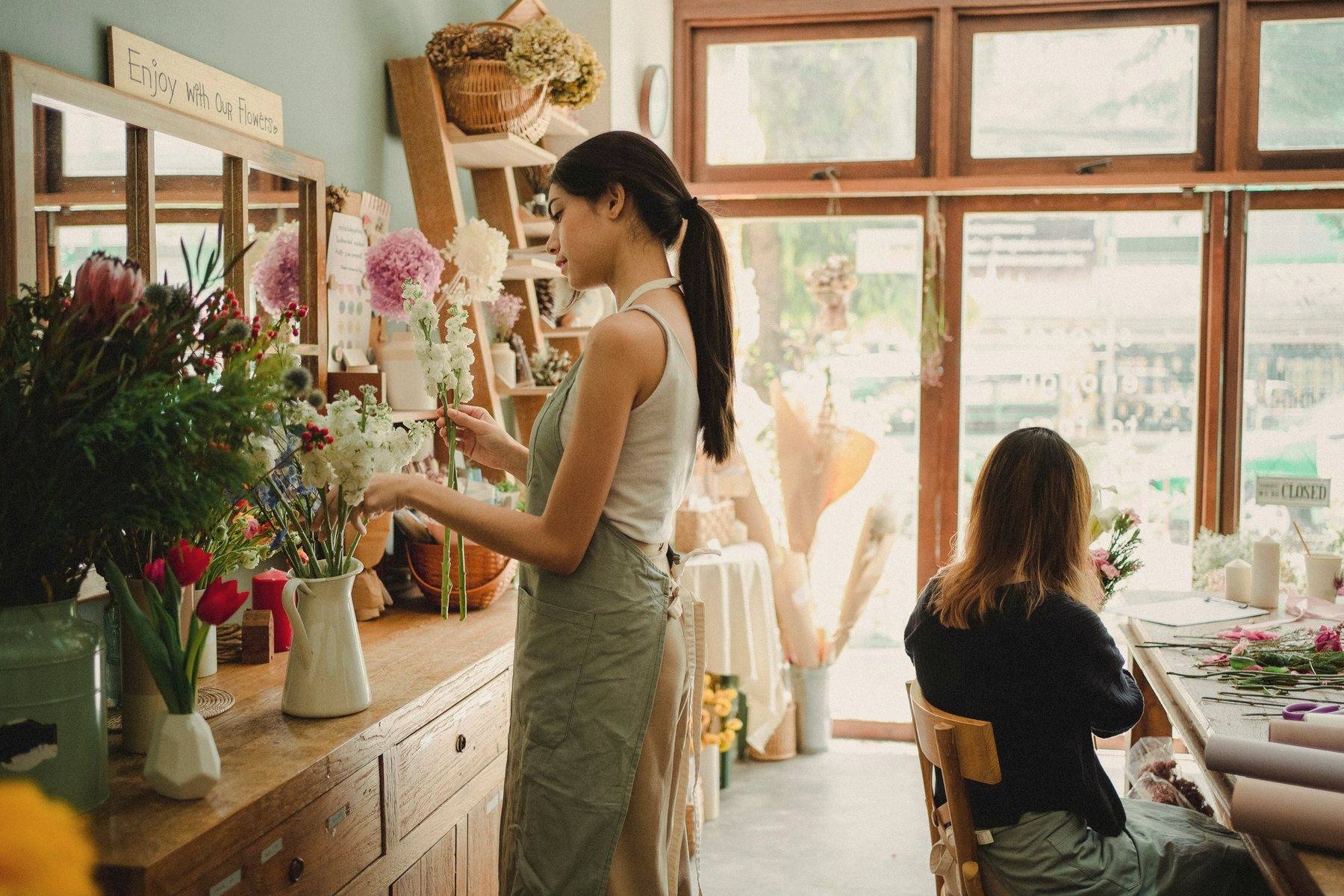 Two people working with flowers in a bright, wood-panelled studio