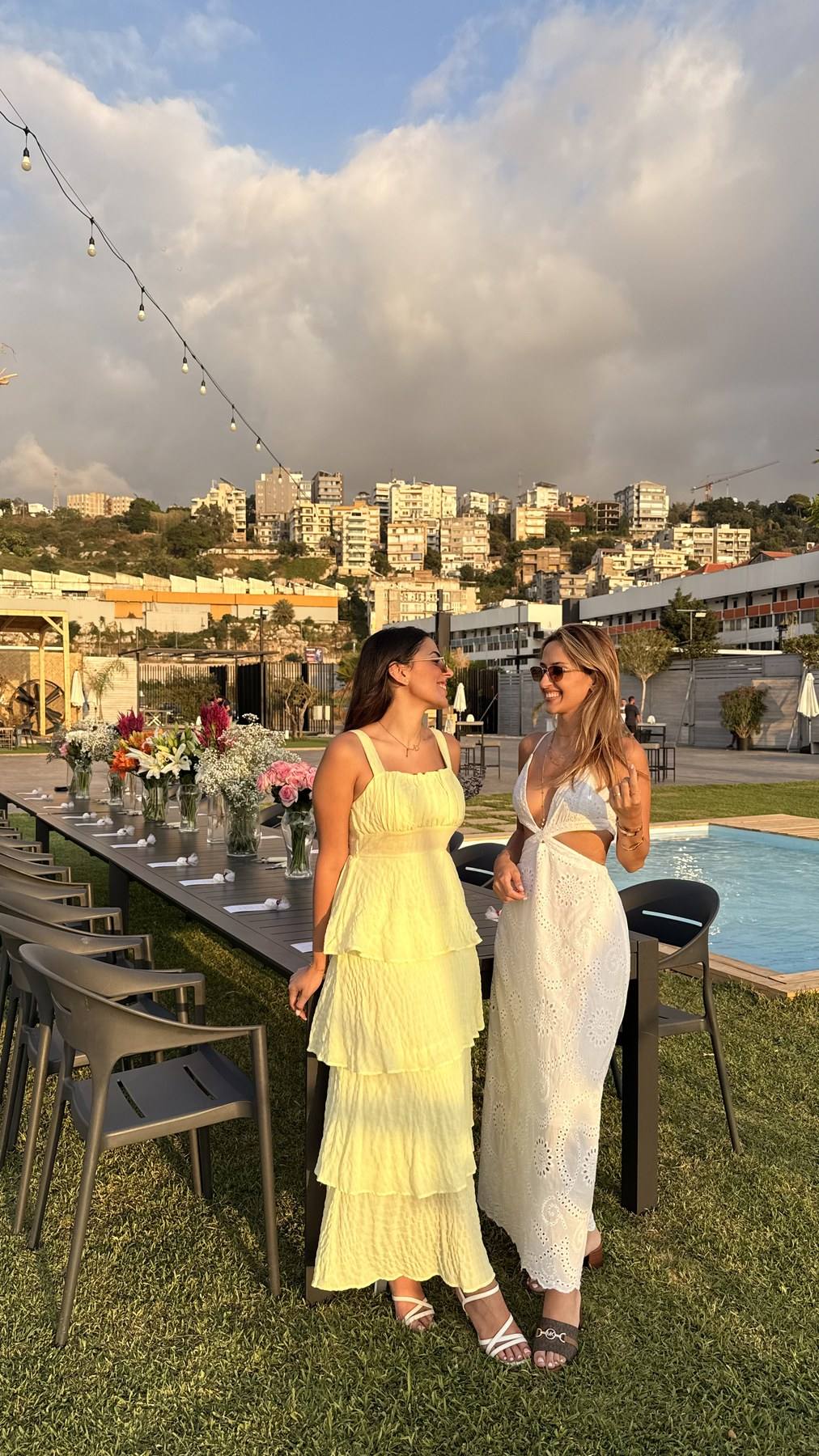 The two founders of Zéïa standing beside a long table set with flowers at a sunset event