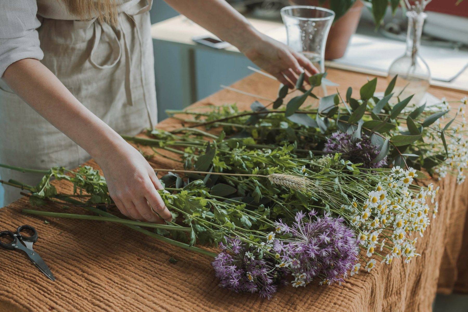 Stems of greenery and lavender laid out across a long wooden table