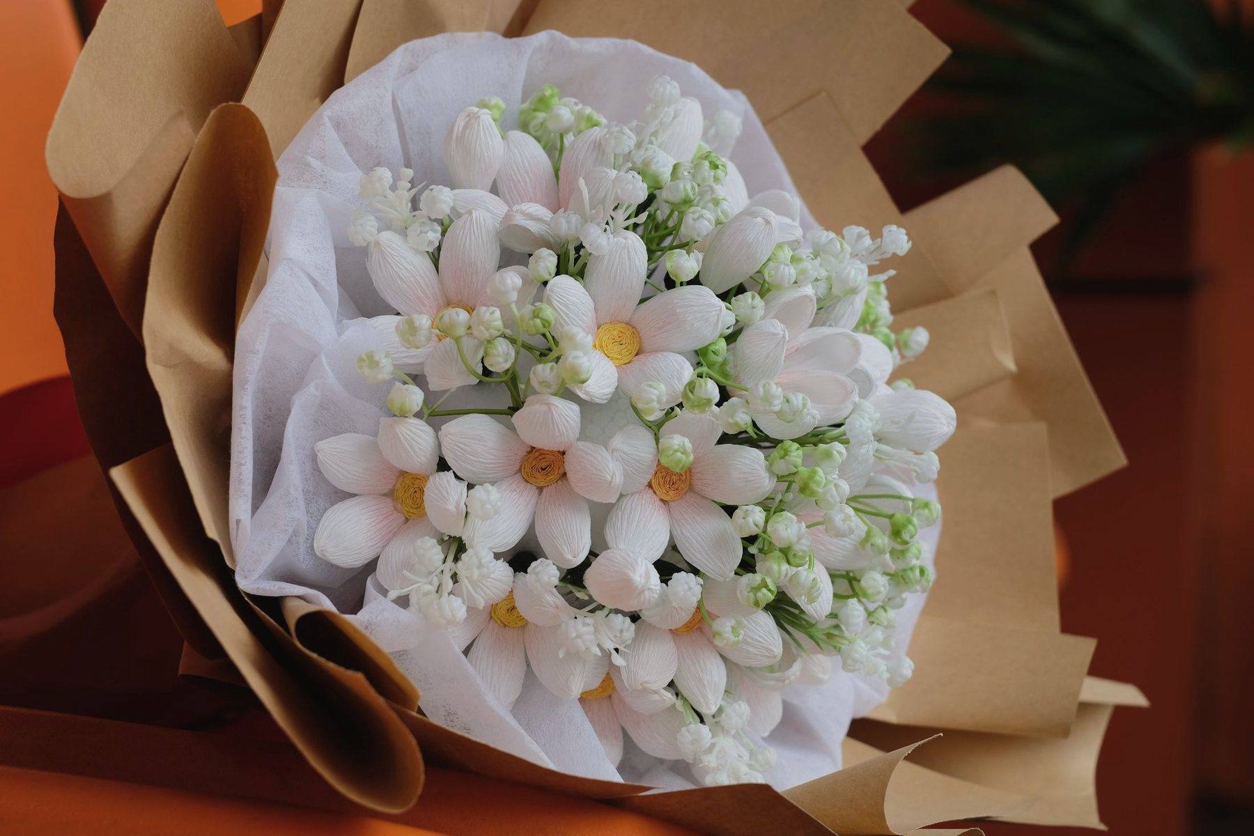 A bouquet of small white flowers wrapped in kraft paper