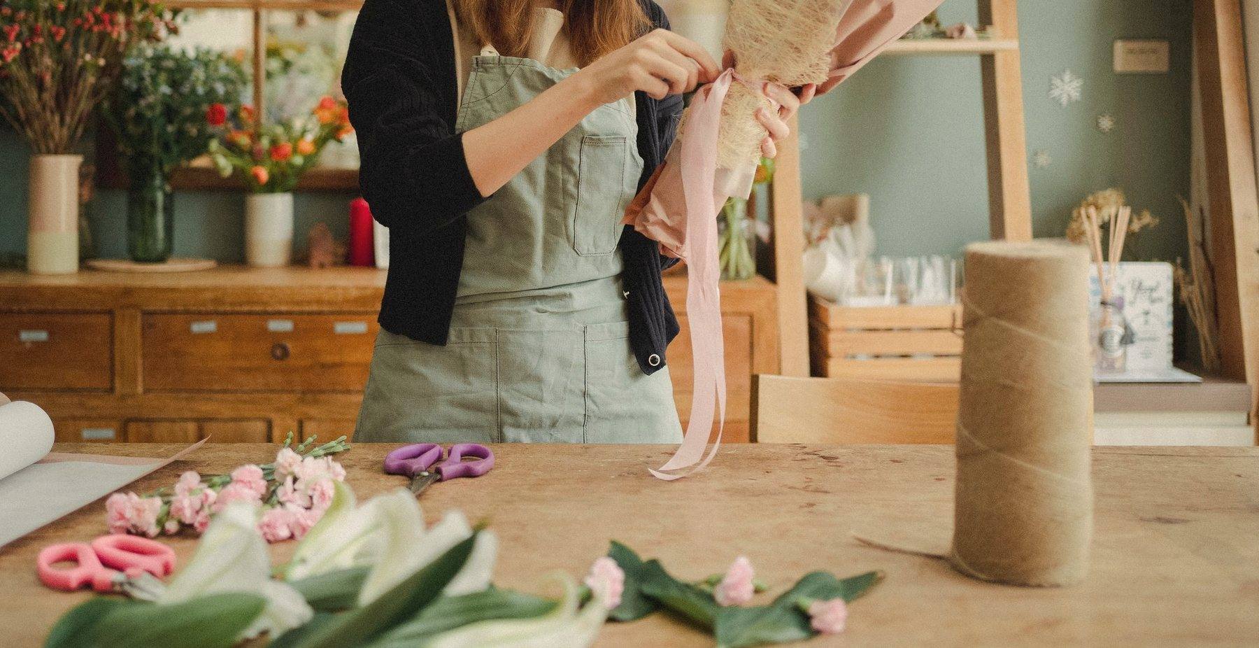 A workshop table with ribbon, twine and cut flowers