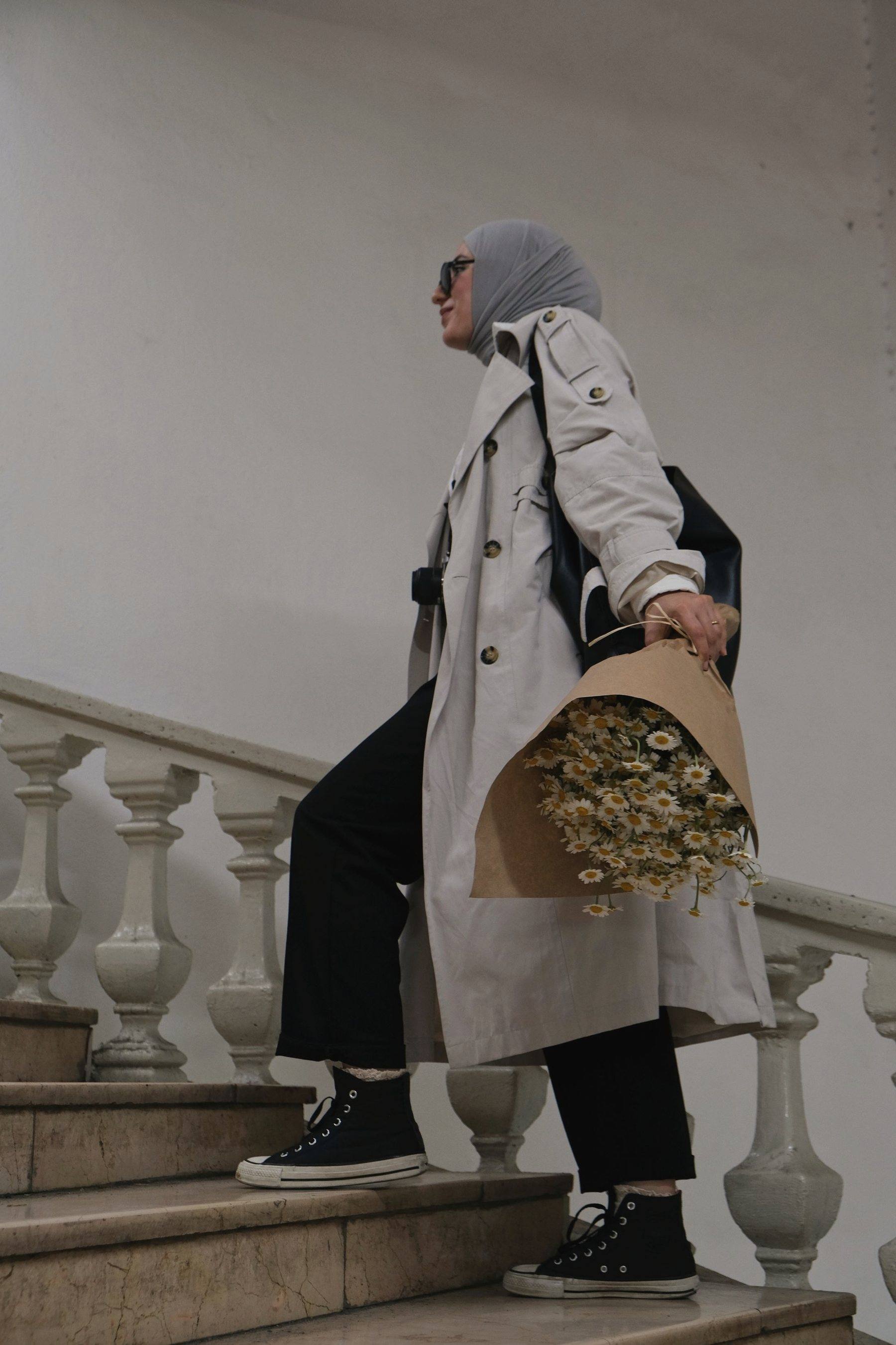 Someone walking down stone stairs carrying a wrapped bouquet